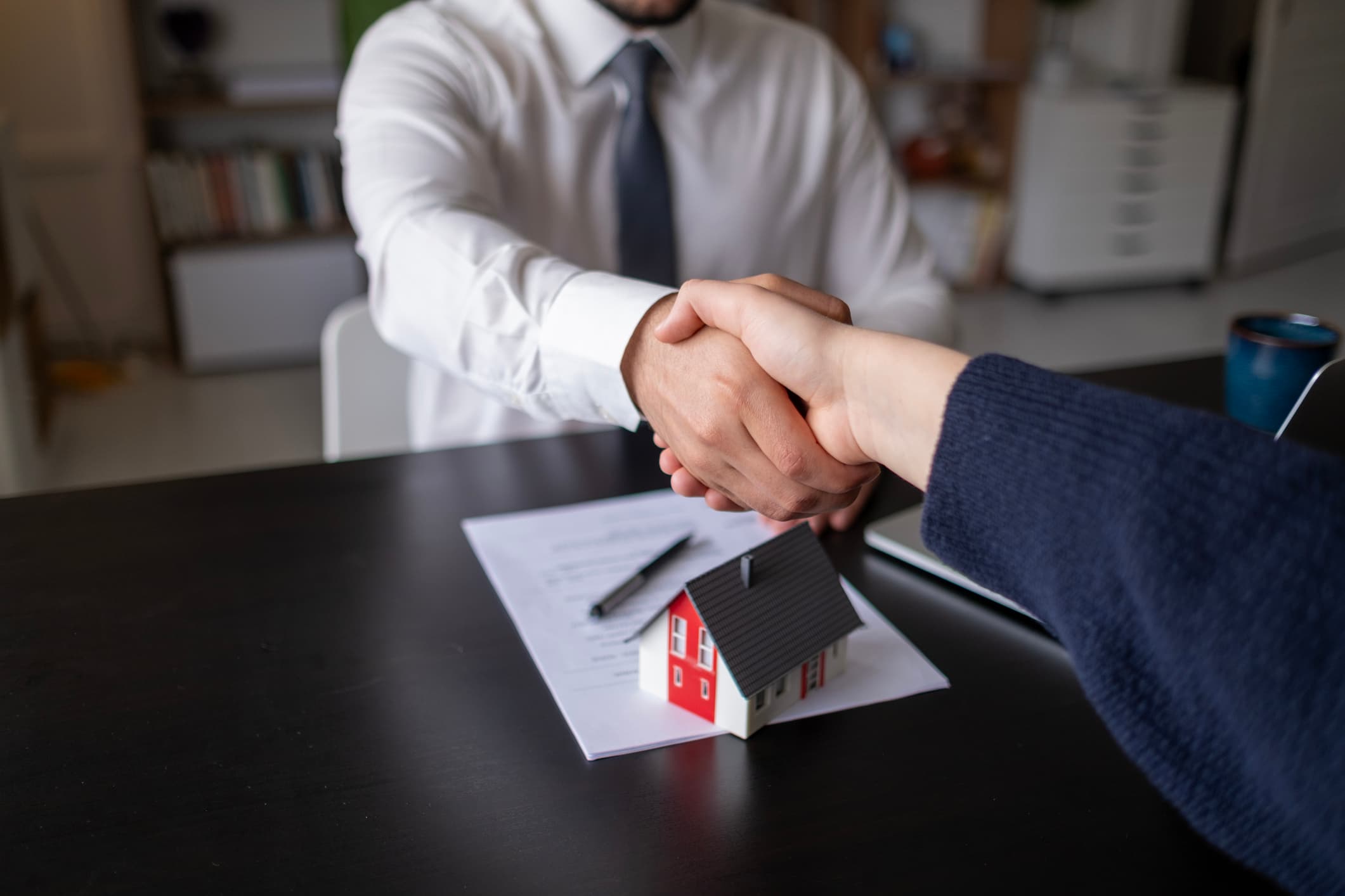 Listing agent and Truehold representative shaking hands over a signed purchase agreement