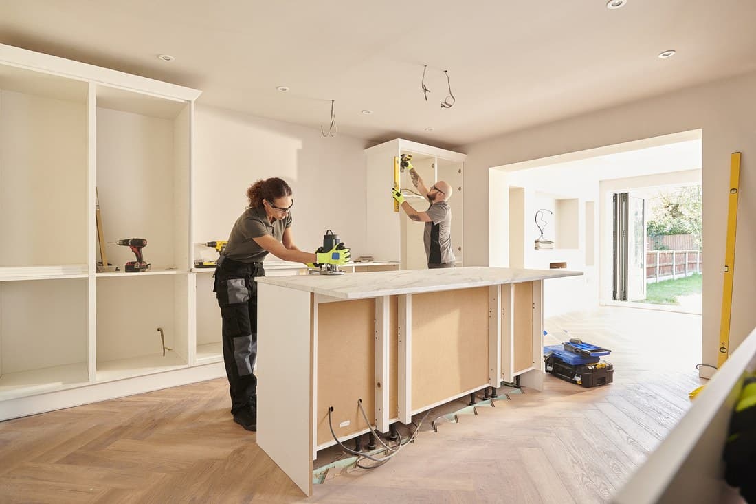 Two contractors installing kitchen cabinets during a home renovation project
